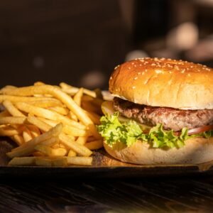 Close-up of a tasty cheeseburger and crispy french fries on a wooden platter.